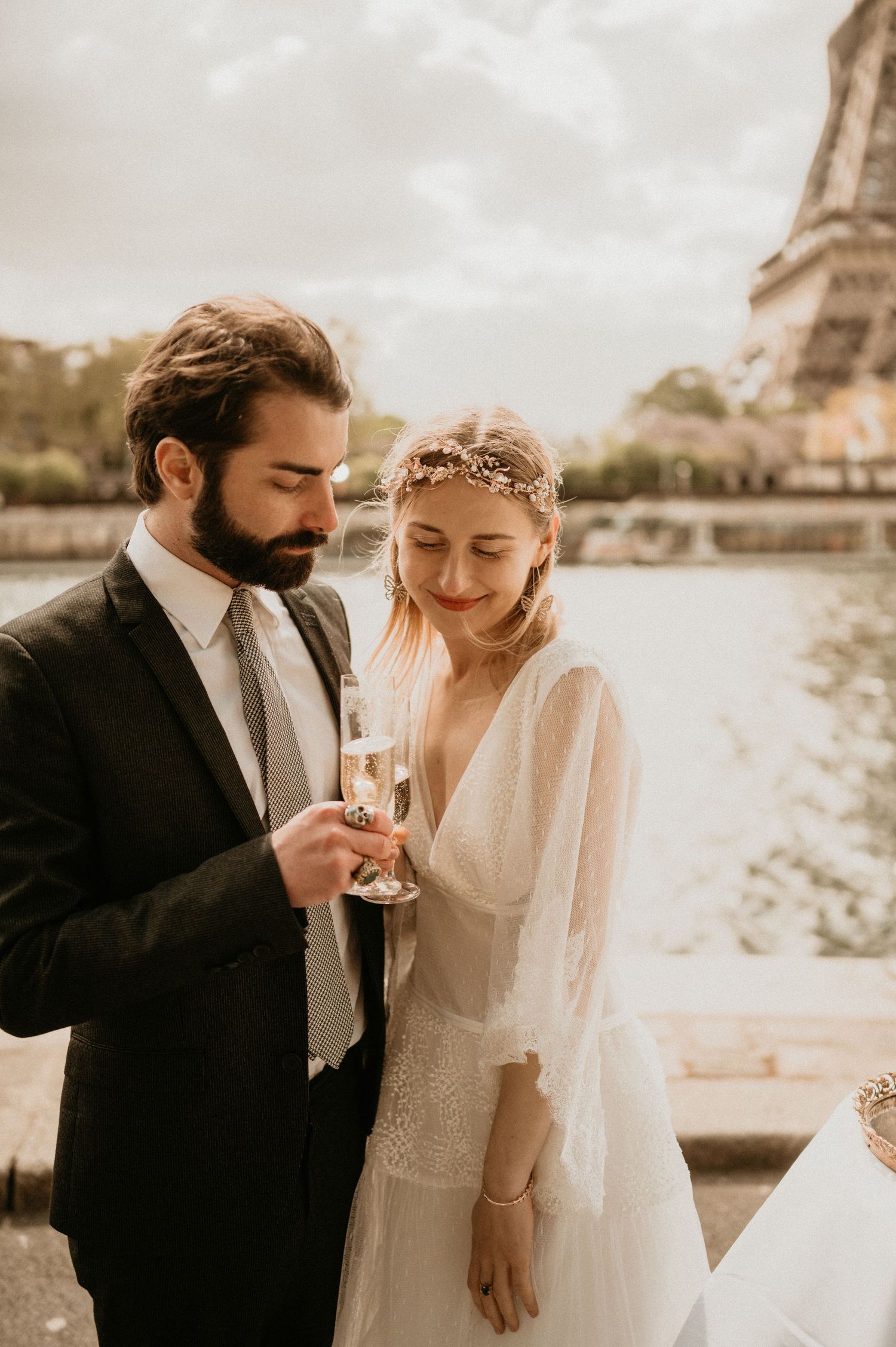 Bride and groom share champagne with Eiffel Tower in background during Paris wedding photoshoot.