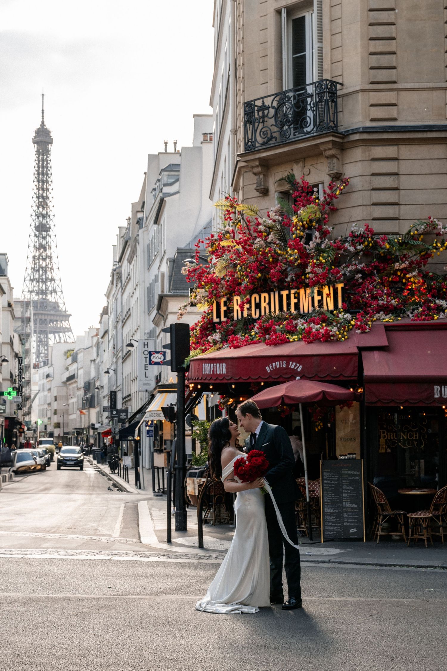 A romantic wedding photo shoot on a charming Parisian street with the Eiffel Tower visible in the background.