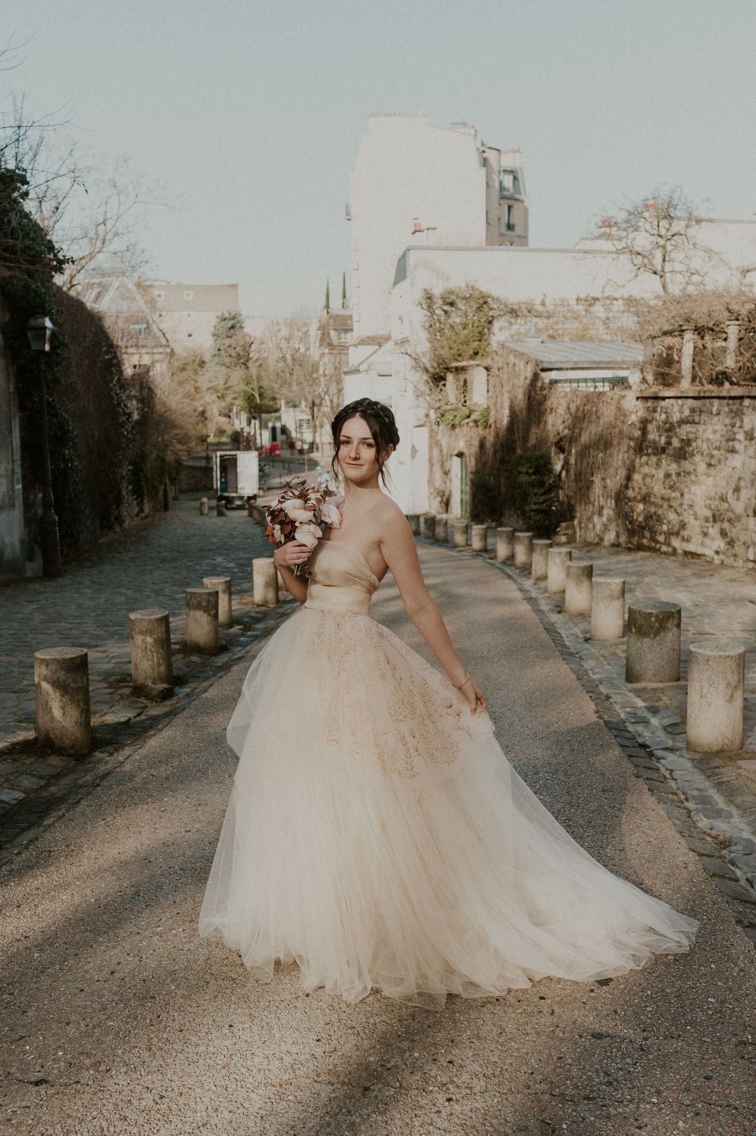 Elegant bridal portrait on a charming European street with stone walls and pillars.