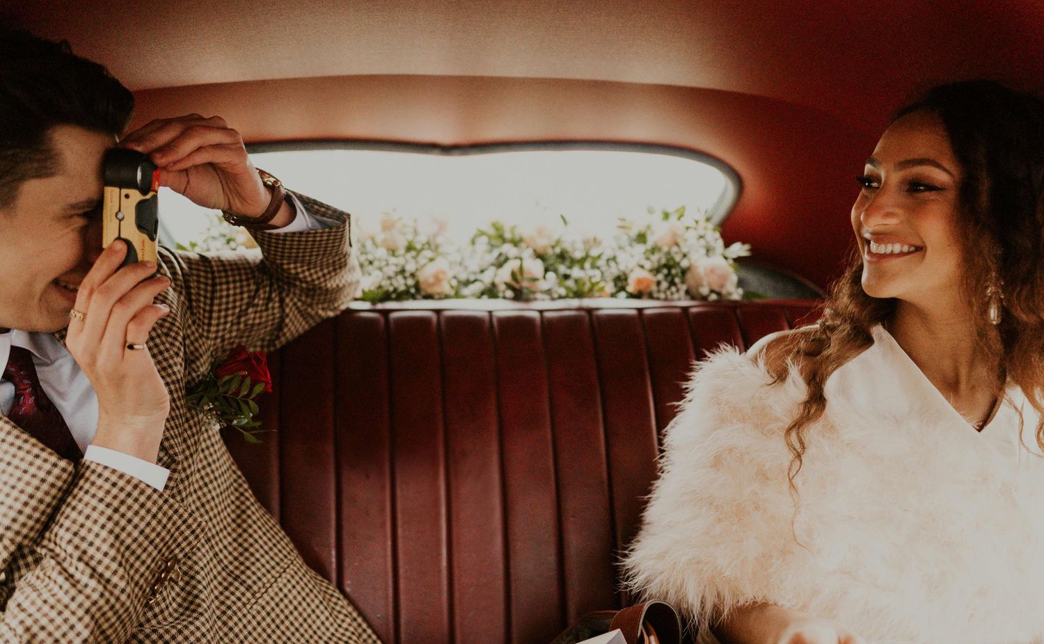 A joyful moment captured inside a vintage car with red leather seats.