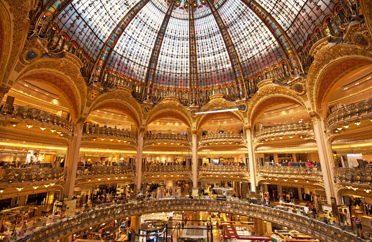 Ornate glass dome ceiling of Galeries Lafayette department store interior in Paris.
