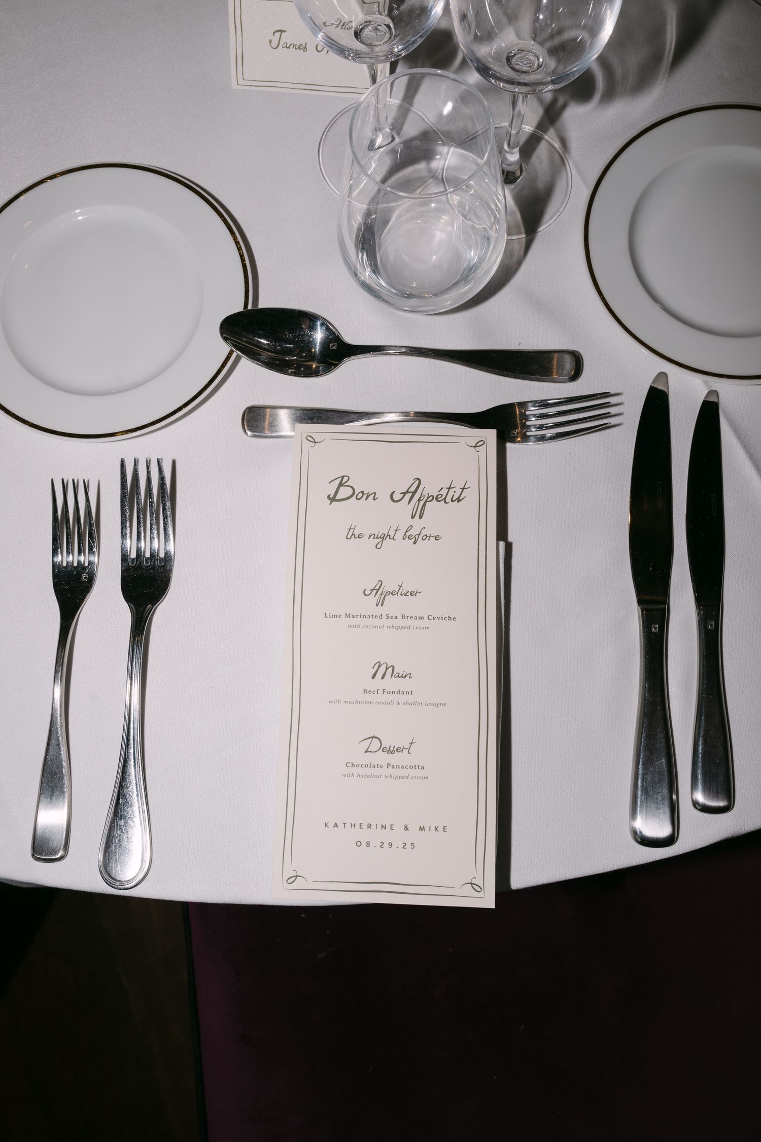 Elegant place settings with menu cards, wine glasses and silverware arranged on a formal dining table.