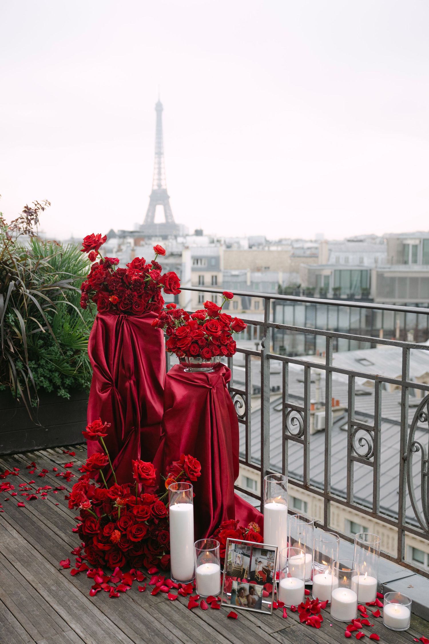 Romantic Paris rooftop proposal setup with red roses, velvet draping, candles and Eiffel Tower view.