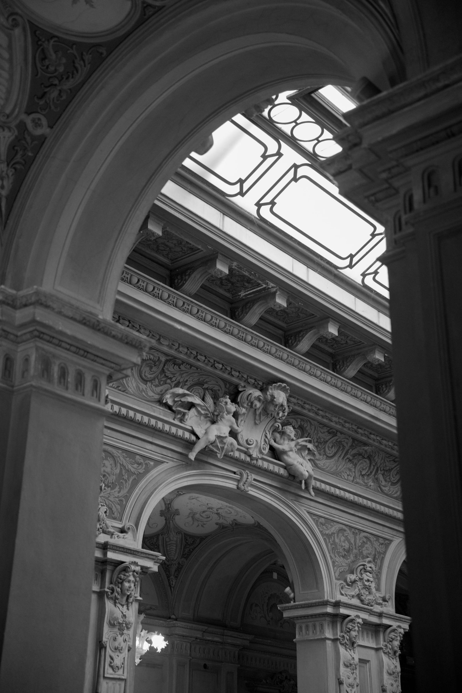 Black and white photo of ornate Baroque architectural arches with sculpted figures and decorative moldings in a grand interior.