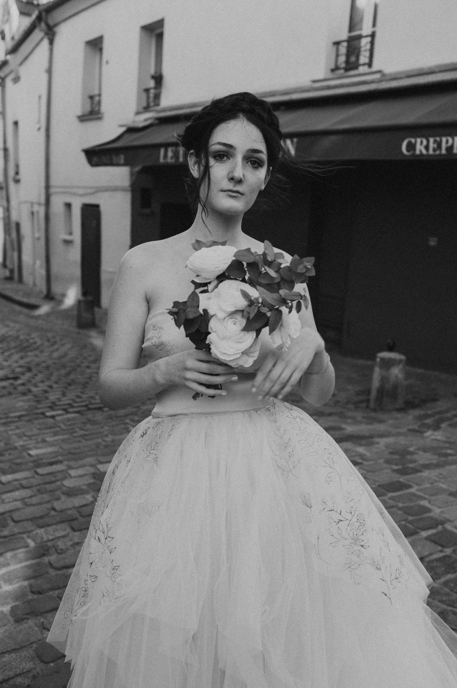 A classic black and white bridal portrait with a structured ball gown and floral bouquet.