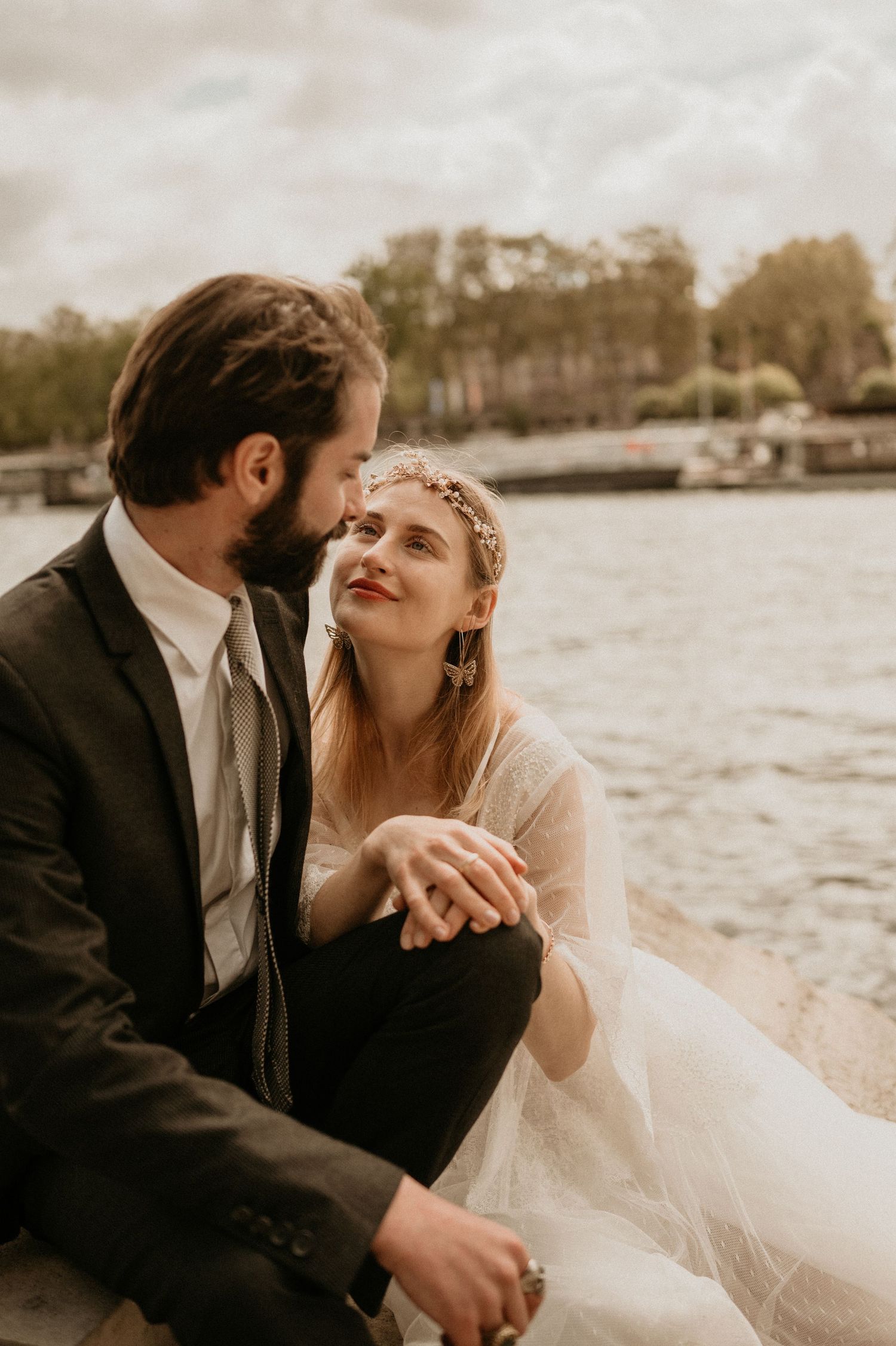 Intimate wedding couple moment captured along the Seine River in warm sepia tones.