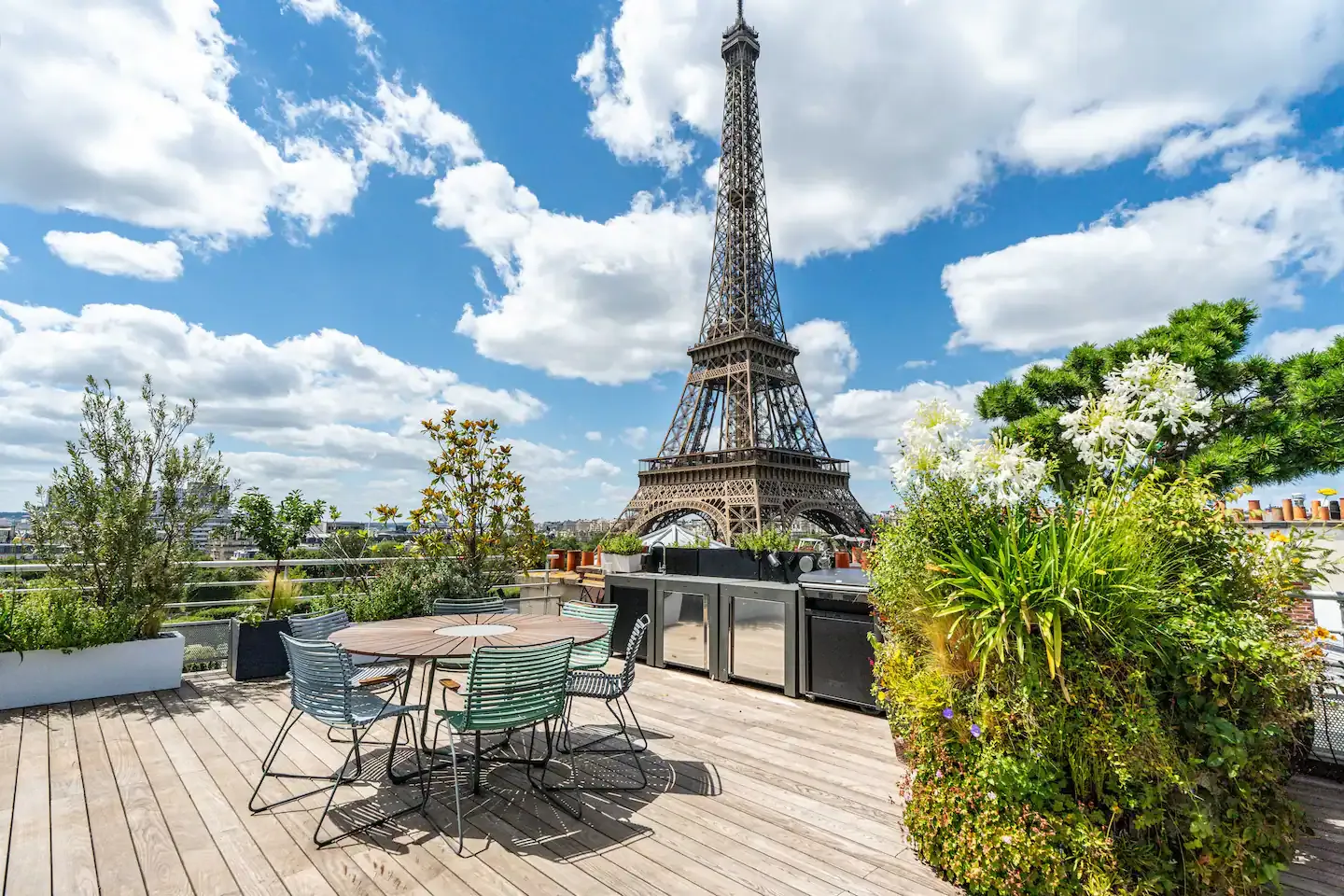 Stunning Eiffel Tower view from balcony with wrought iron furniture and fresh flowers.