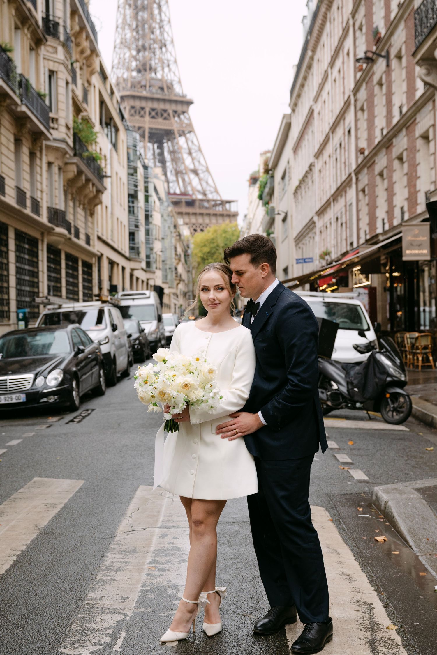 Wedding couple walking down a cobblestone street in Paris with the iconic Eiffel Tower in view.