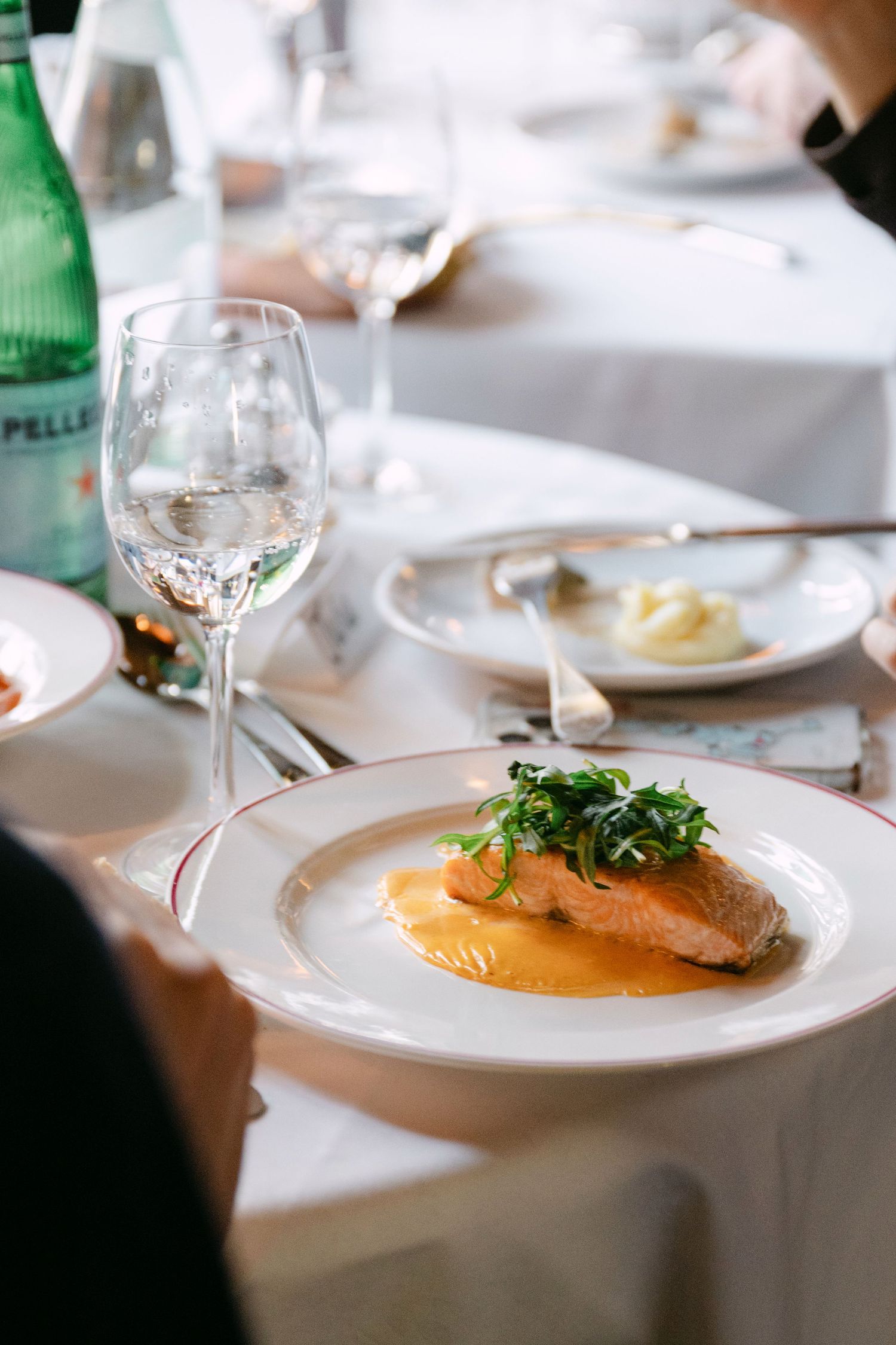 Elegant salmon fillet with greens on orange sauce served at fine dining table.