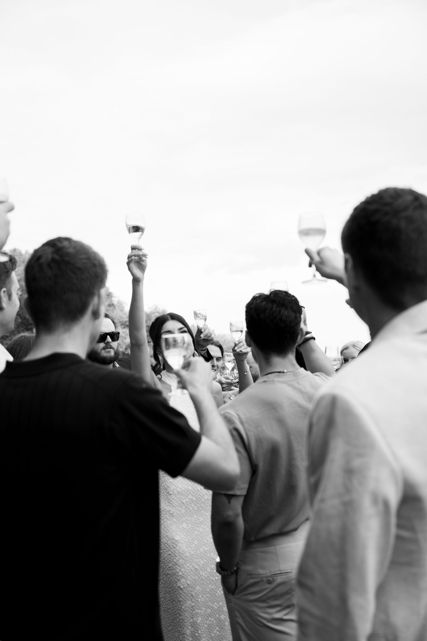 A black and white photo showing a crowd of people with raised arms against an overexposed sky.