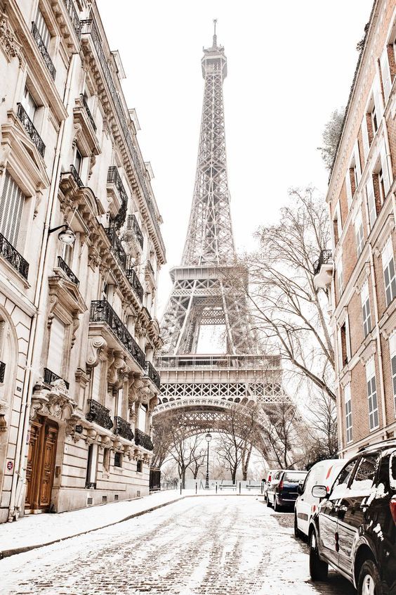 Snow-covered Parisian street with the Eiffel Tower framed by Haussmann buildings in winter.
