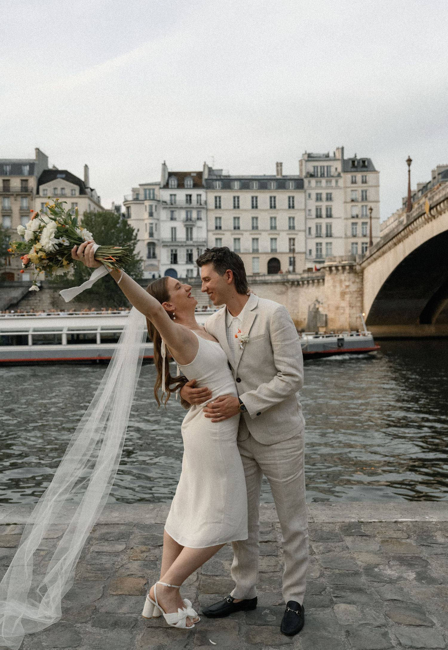 A joyful celebration by the Seine River with historic Parisian architecture in the background.