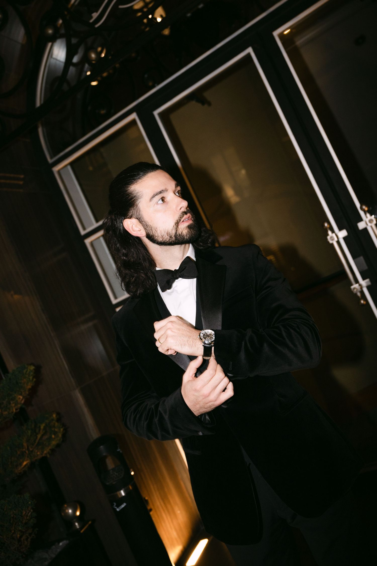 A person in dark clothing looks to the side while standing in a dimly lit interior space.