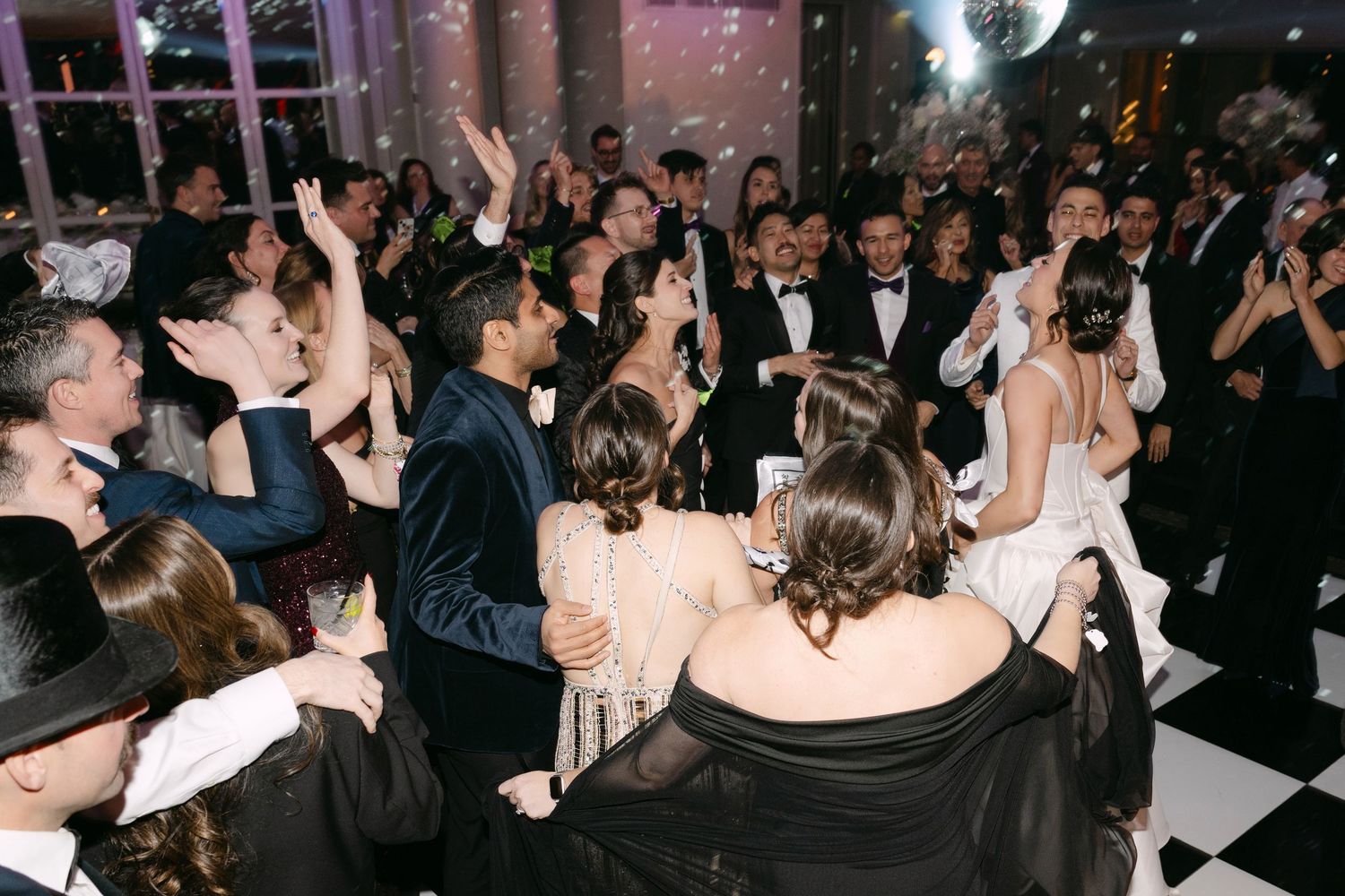 Lively wedding reception dance floor filled with guests celebrating under sparkling lights.