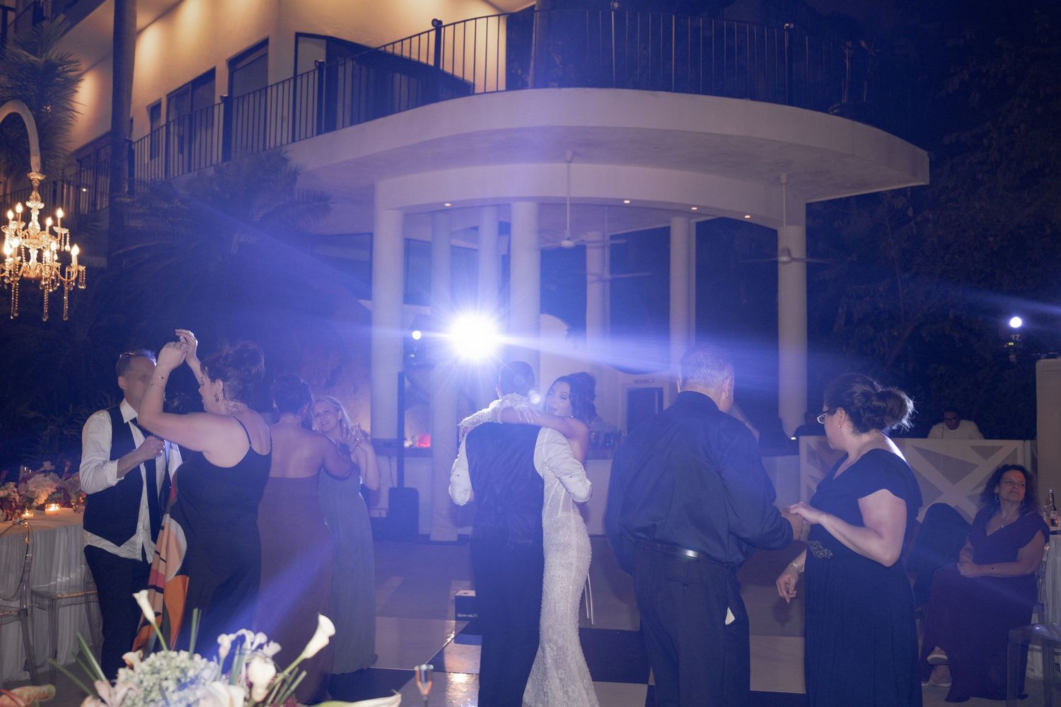 Bride and groom share first dance at elegant outdoor wedding reception with guests and decorative lighting.