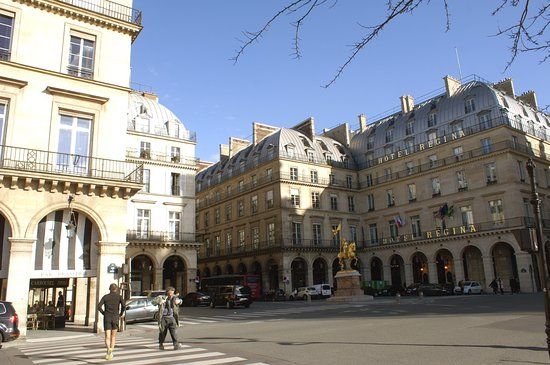 Historic square in Paris with classic Haussmann architecture and stone arcades.