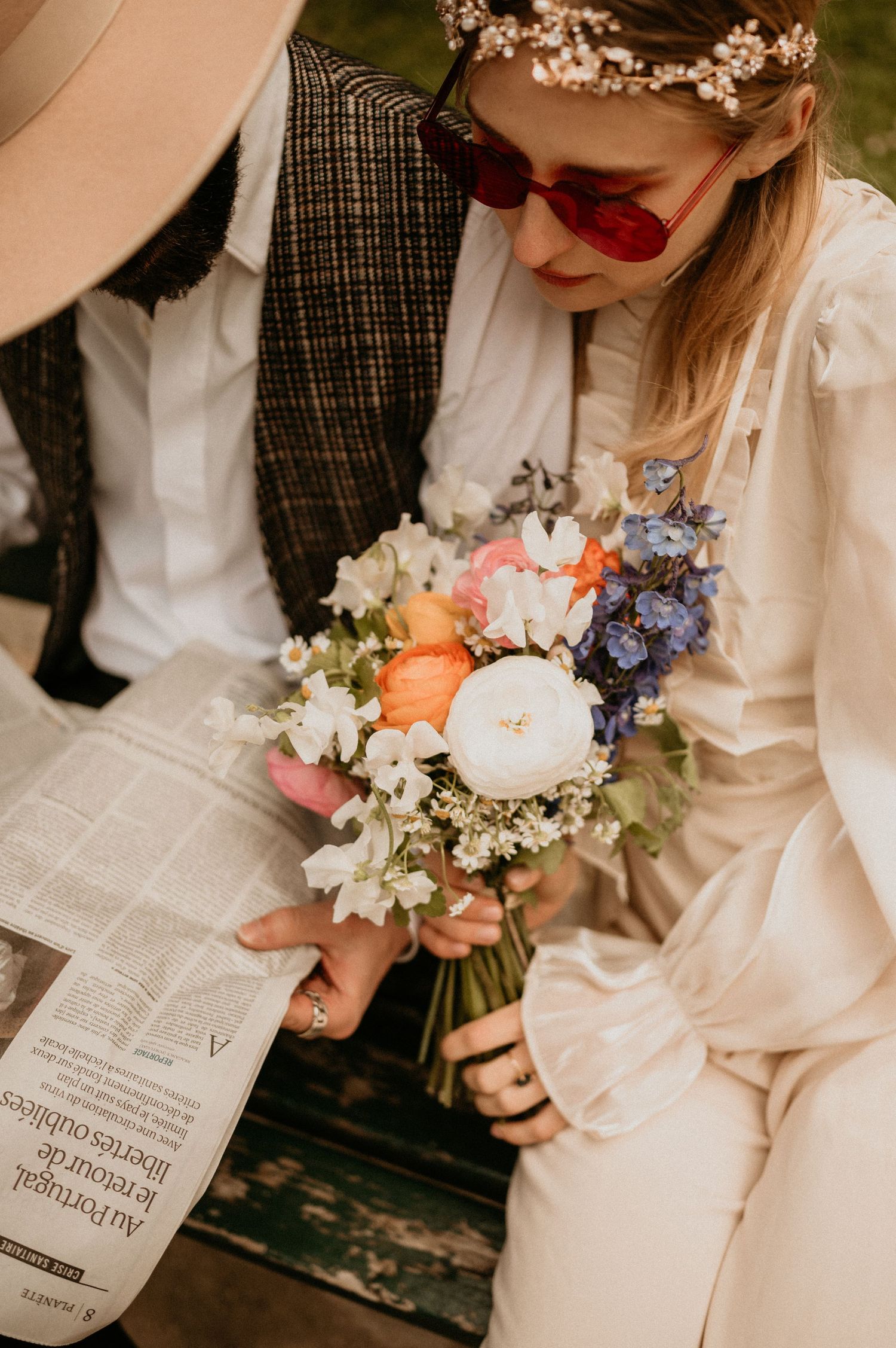 Close-up shot of a beautiful floral bouquet with coral roses and blue delphinium next to a newspaper.
