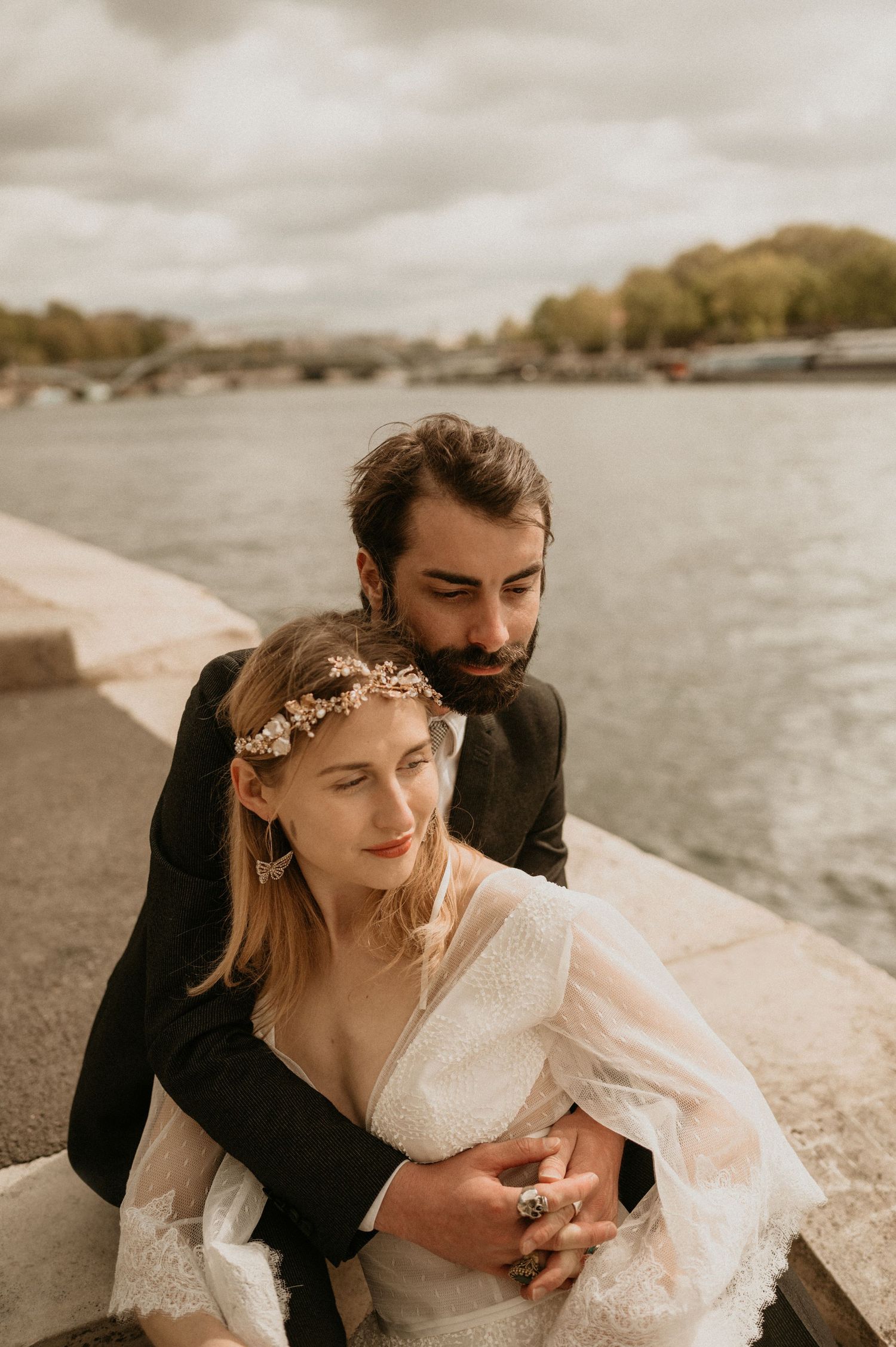 Romantic autumn wedding portrait with couple embracing by the Seine River.
