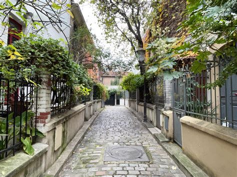 A charming cobblestone alley with ivy-covered walls and ornate gates leading to a hidden courtyard.