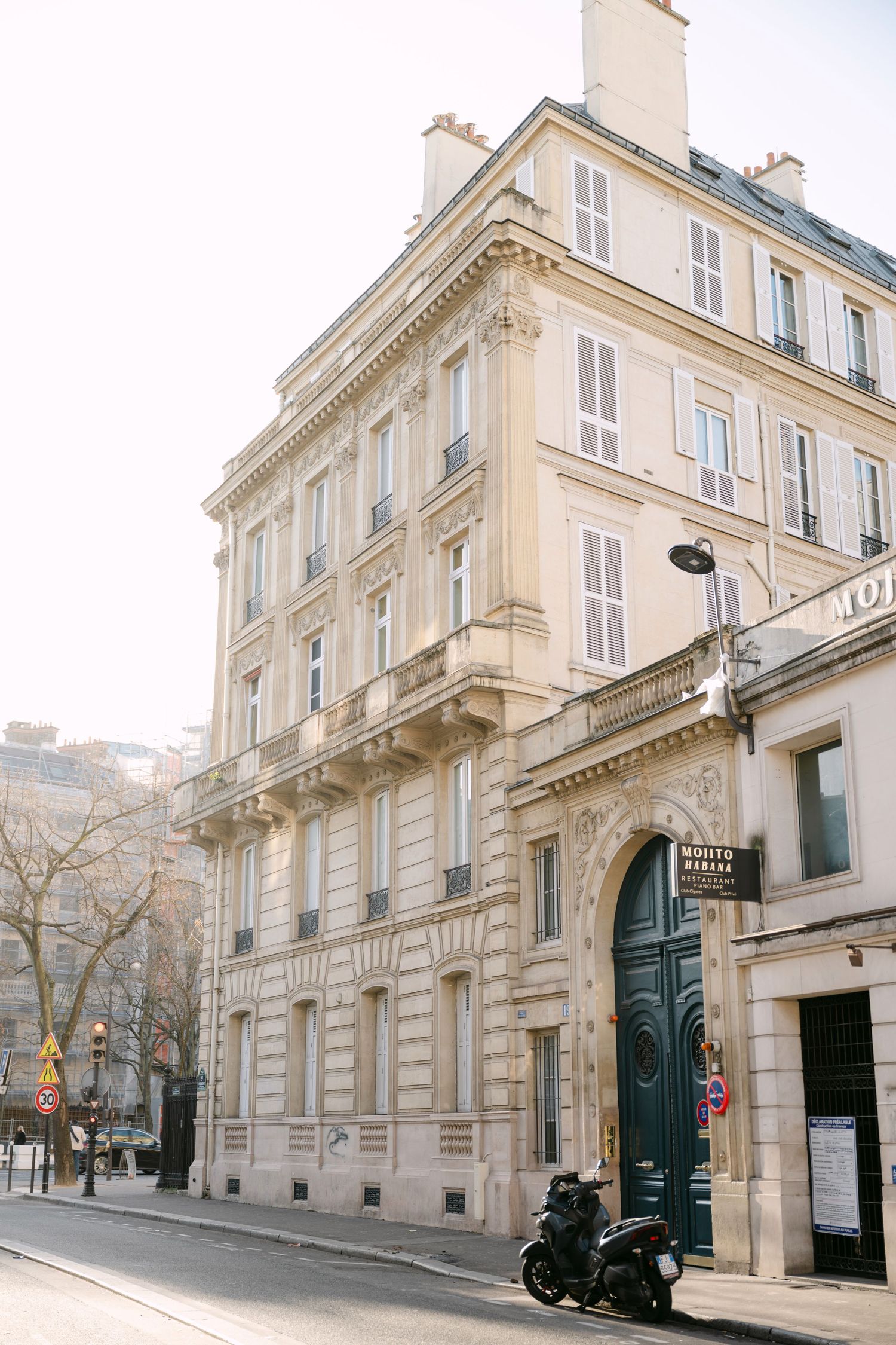 Classic Haussmann-style Parisian building corner with motorcycle parked outside.