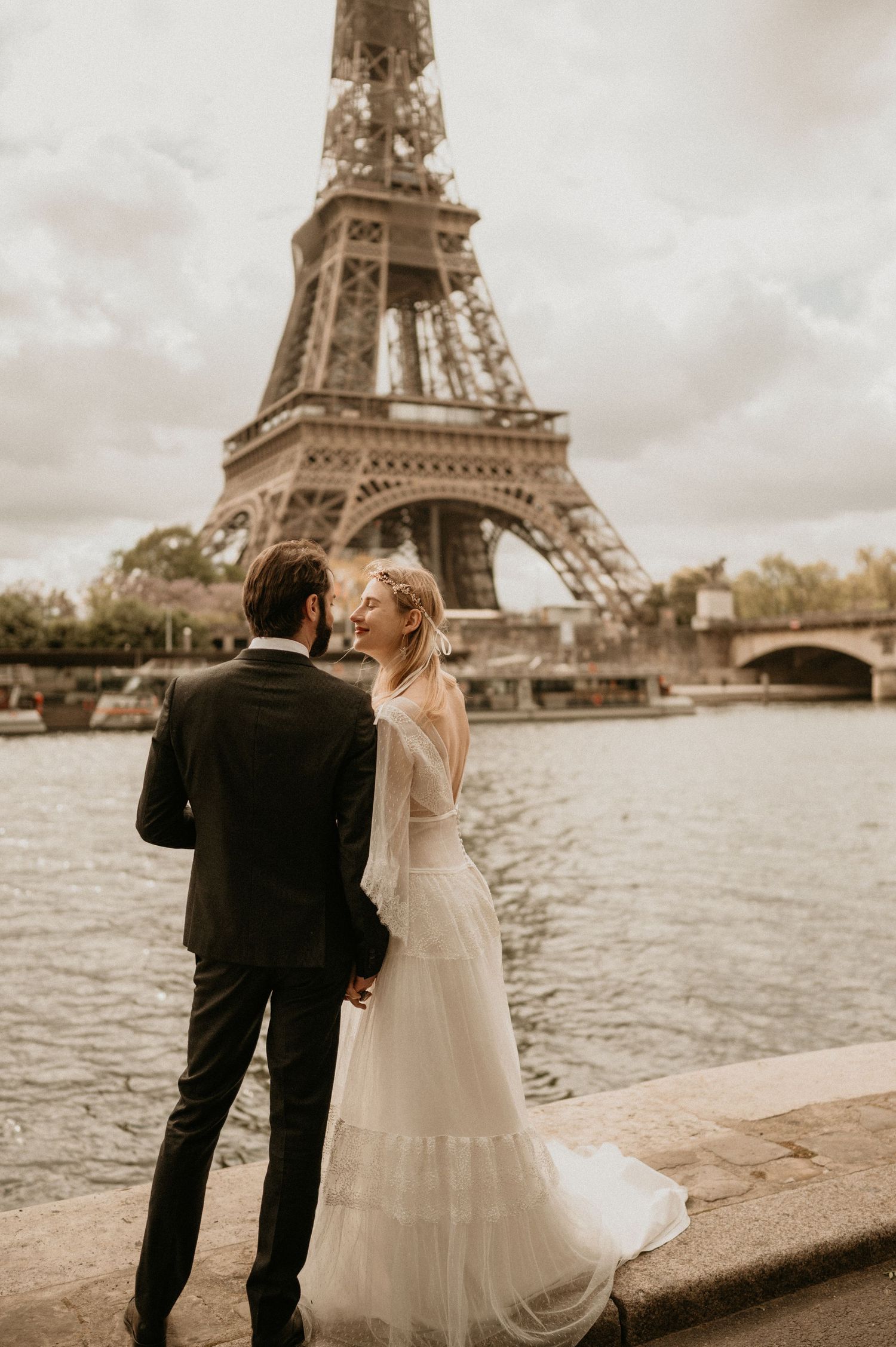 Romantic wedding portrait of couple embracing by the Seine River in Paris.
