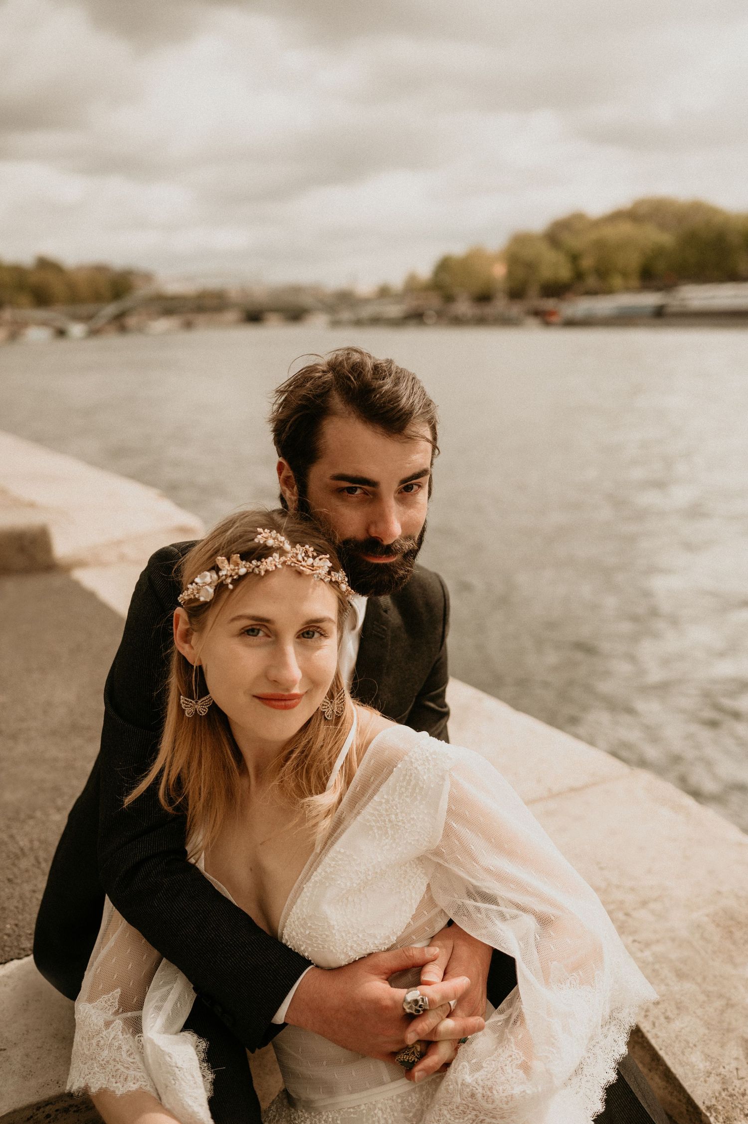 Intimate wedding portrait showing couple in warm embrace along Parisian riverside.