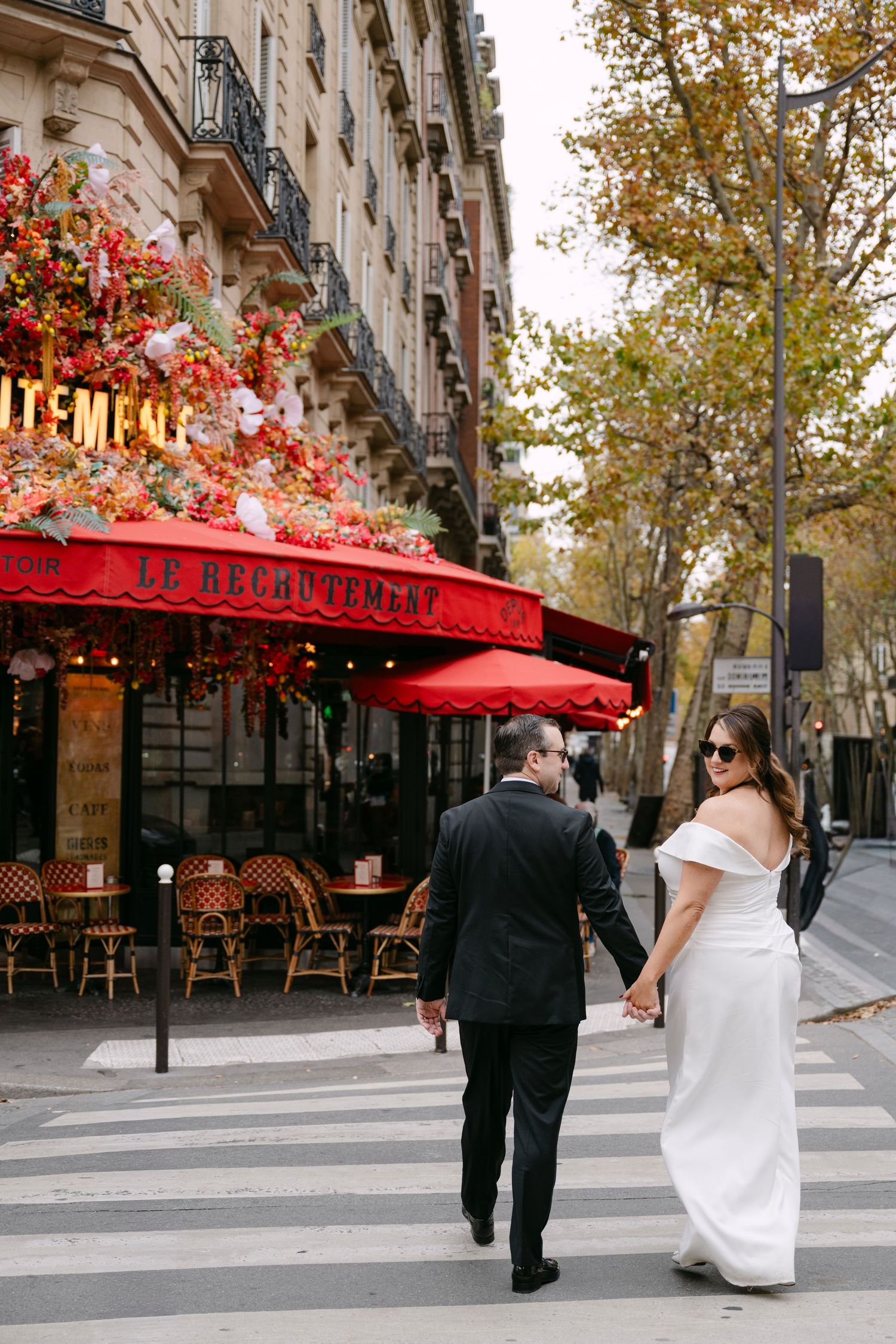 Diners enjoy atmosphere at traditional Parisian sidewalk cafe with red awning.
