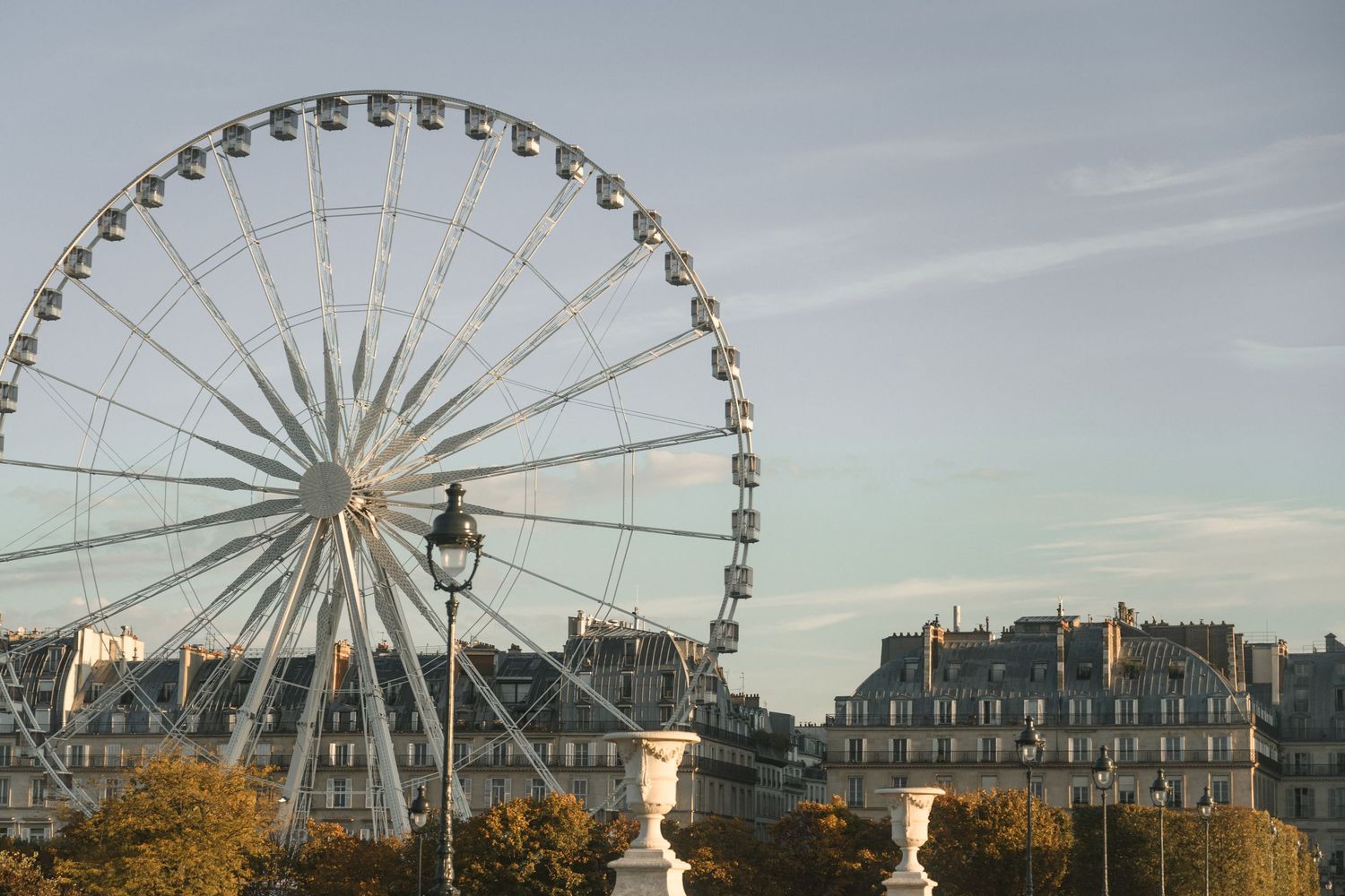 Large Ferris wheel silhouetted against cloudy sky in a French city landscape.