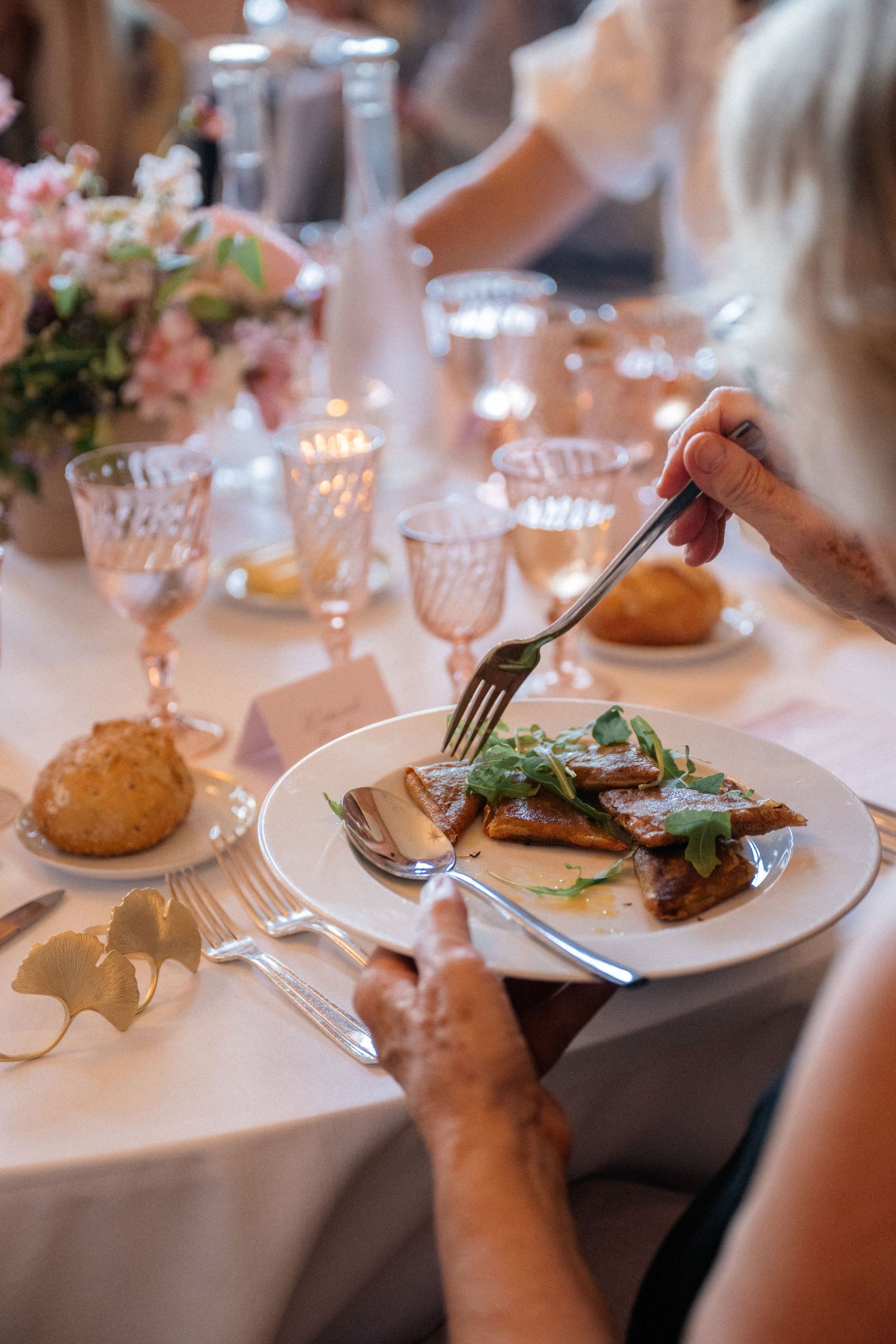 Elegant wedding dinner plate with braised meat and microgreens, served on white china at a candlelit reception table.
