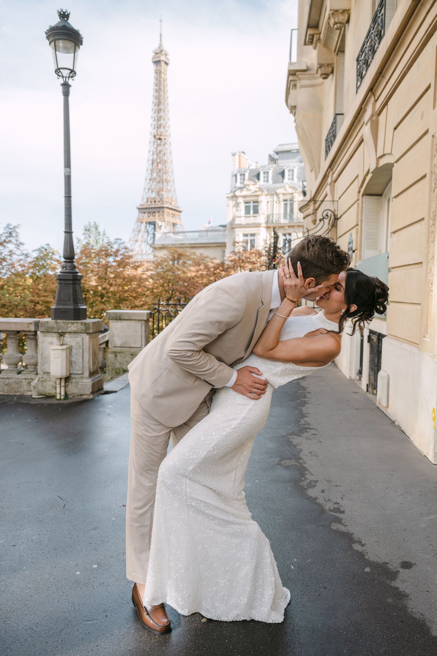 Bride and groom share a romantic dip kiss on a Parisian street with the Eiffel Tower in the background.