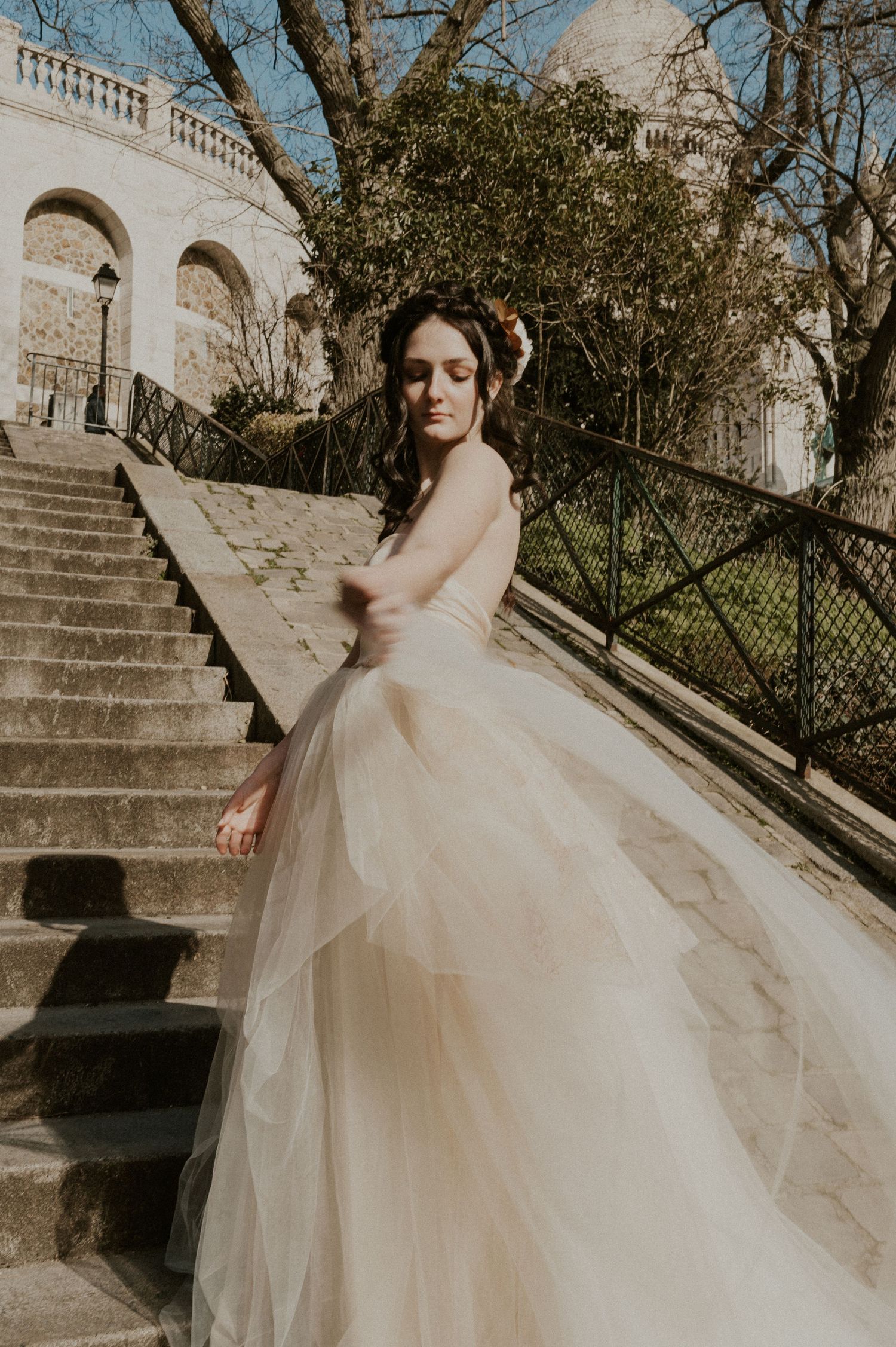 Sun-kissed bridal portrait featuring flowing tulle gown against classic architecture.