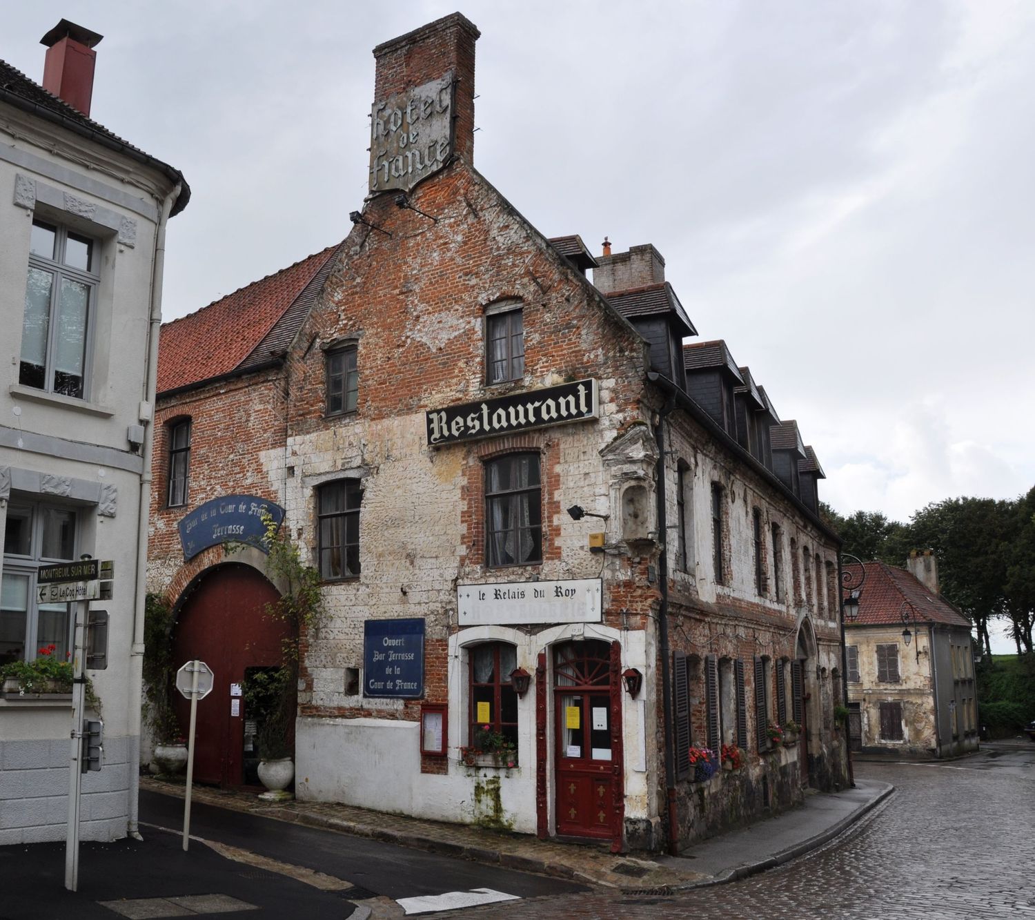 Historic brick restaurant building with rustic facade at a quaint street corner in France.