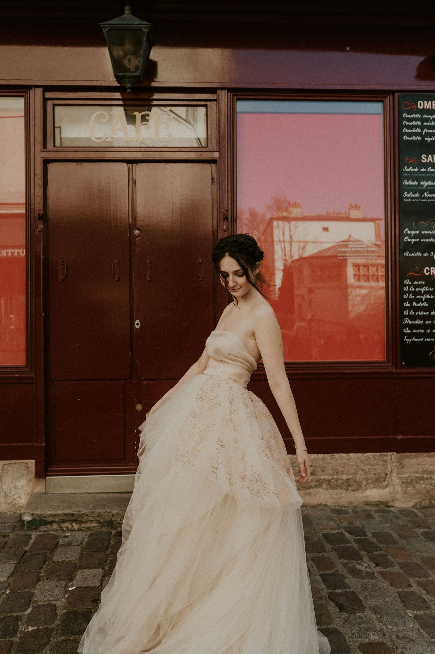 Romantic bridal portrait showcasing layered tulle gown against rustic restaurant exterior.