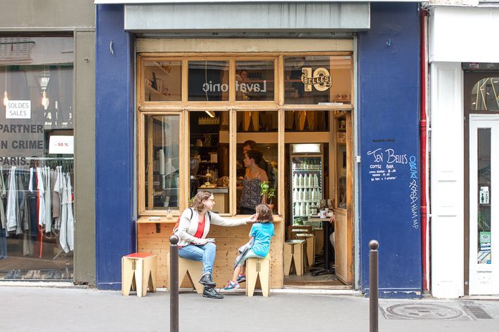 Small boutique coffee shop with rustic wooden exterior seating in Paris.
