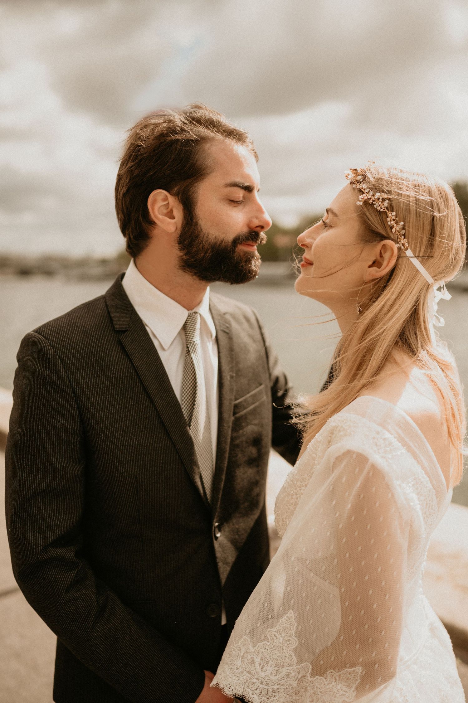 Intimate wedding portrait showing couple in sunlit moment with bride in lace dress and groom in dark suit.