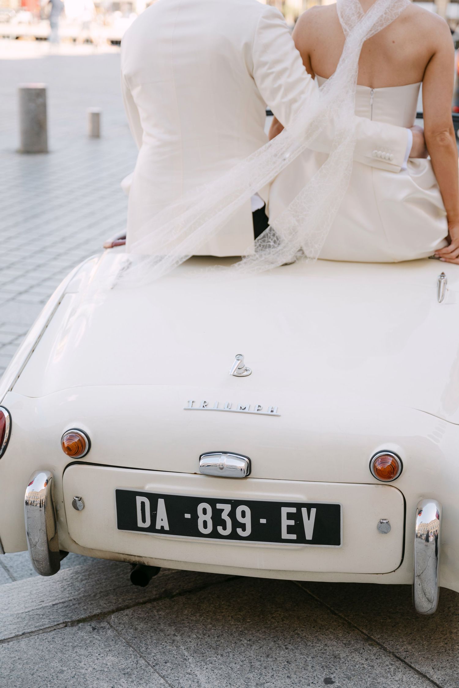Close-up view of a vintage white car's rear end showing a license plate and classic rounded design details.