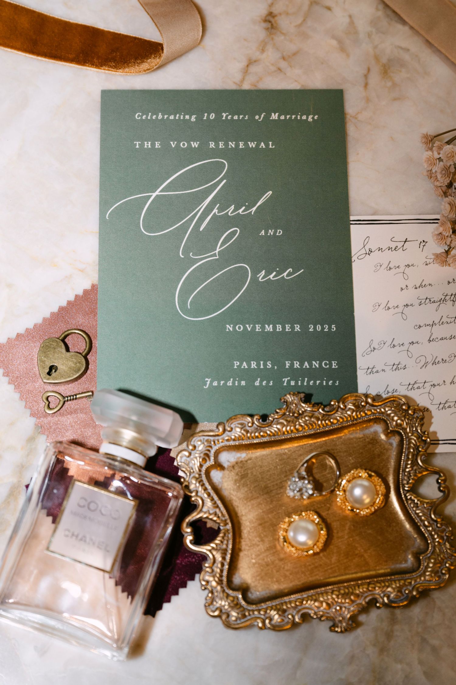 Elegant vow renewal invitation for April and Eric, Paris France, with Chanel perfume, pearl earrings, and gold jewelry tray.
