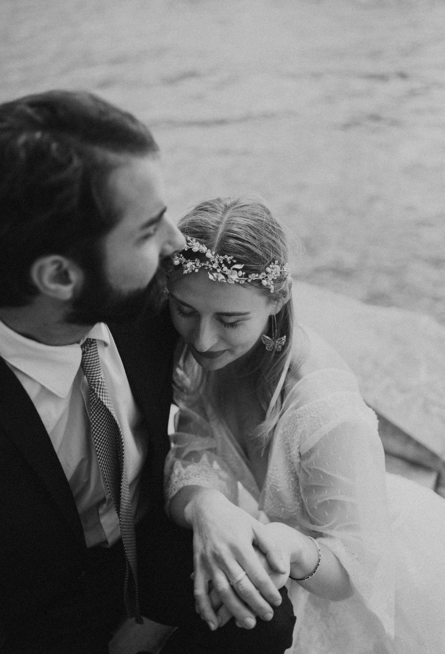 Black and white intimate portrait of newlyweds sharing a tender moment by the water.