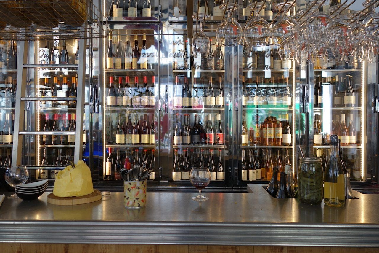 A fully stocked bar counter with glass bottles and liquor display shelves illuminated behind.