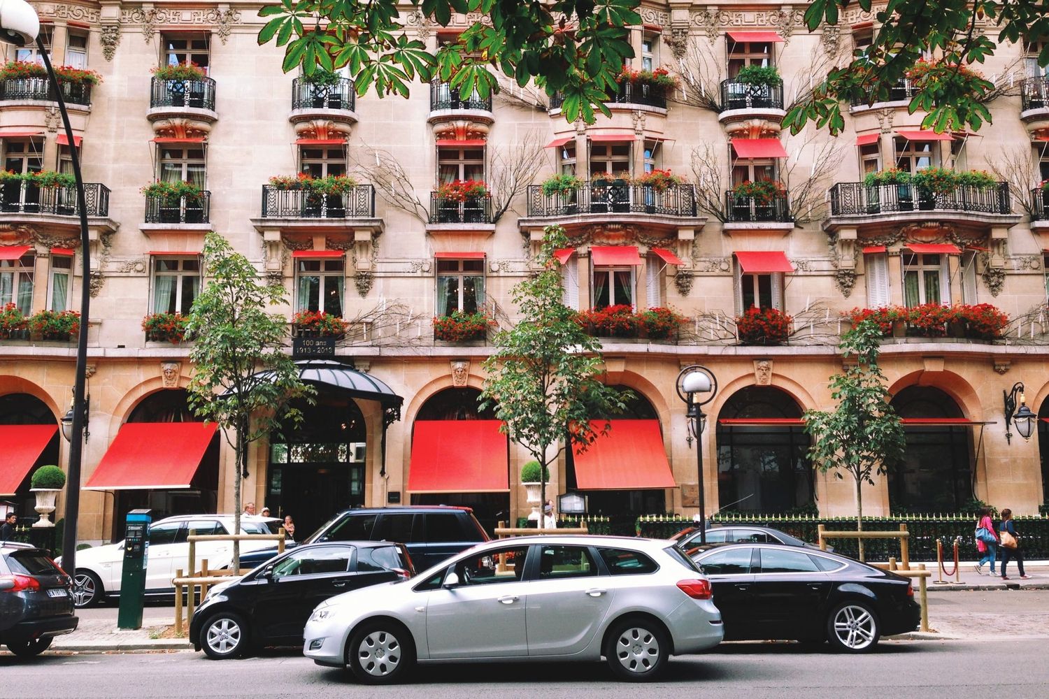 Classic Parisian building with red awnings and rows of ornate balconies along the facade.