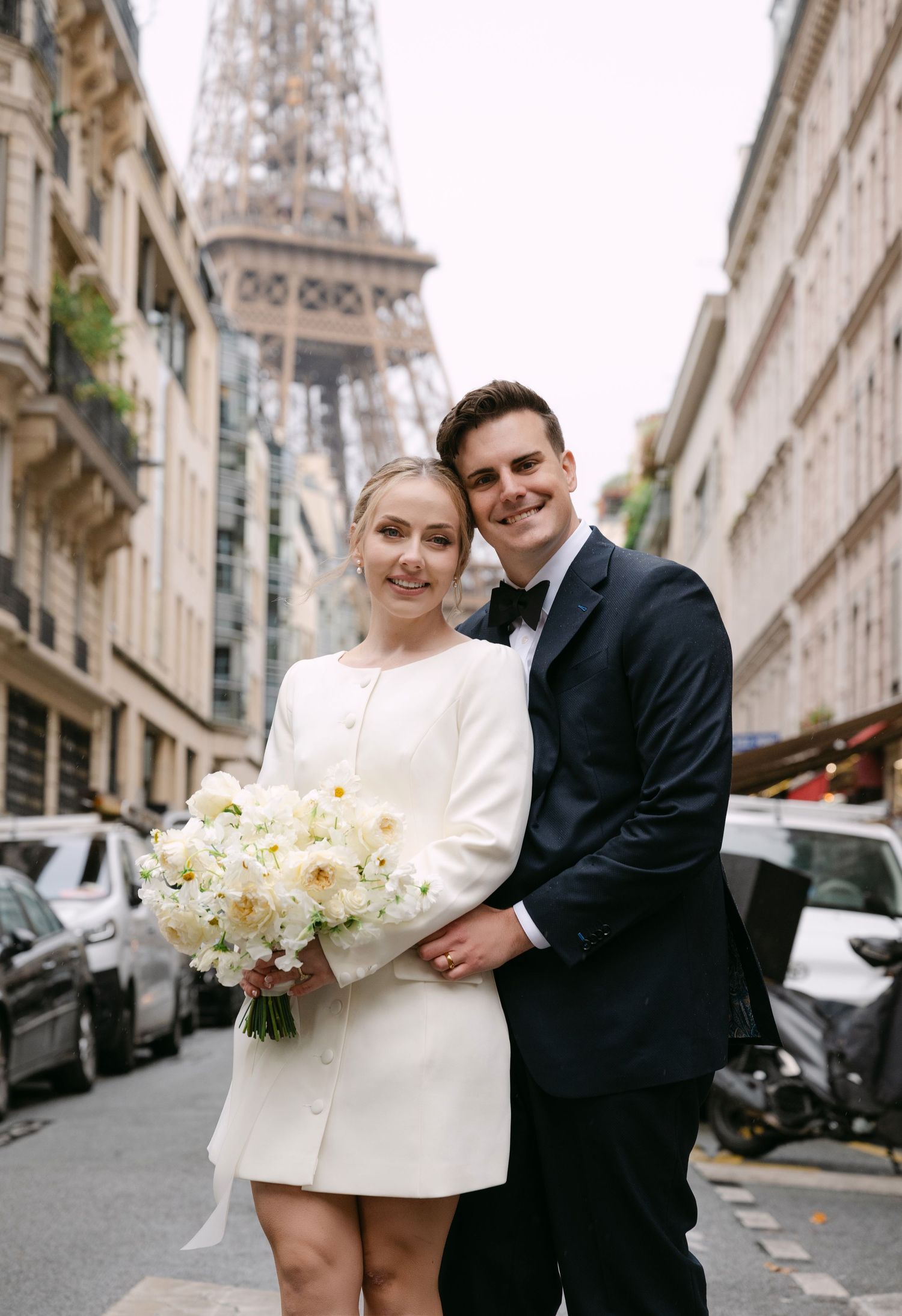 Elegant wedding couple posing on a charming Parisian street with the Eiffel Tower in view.