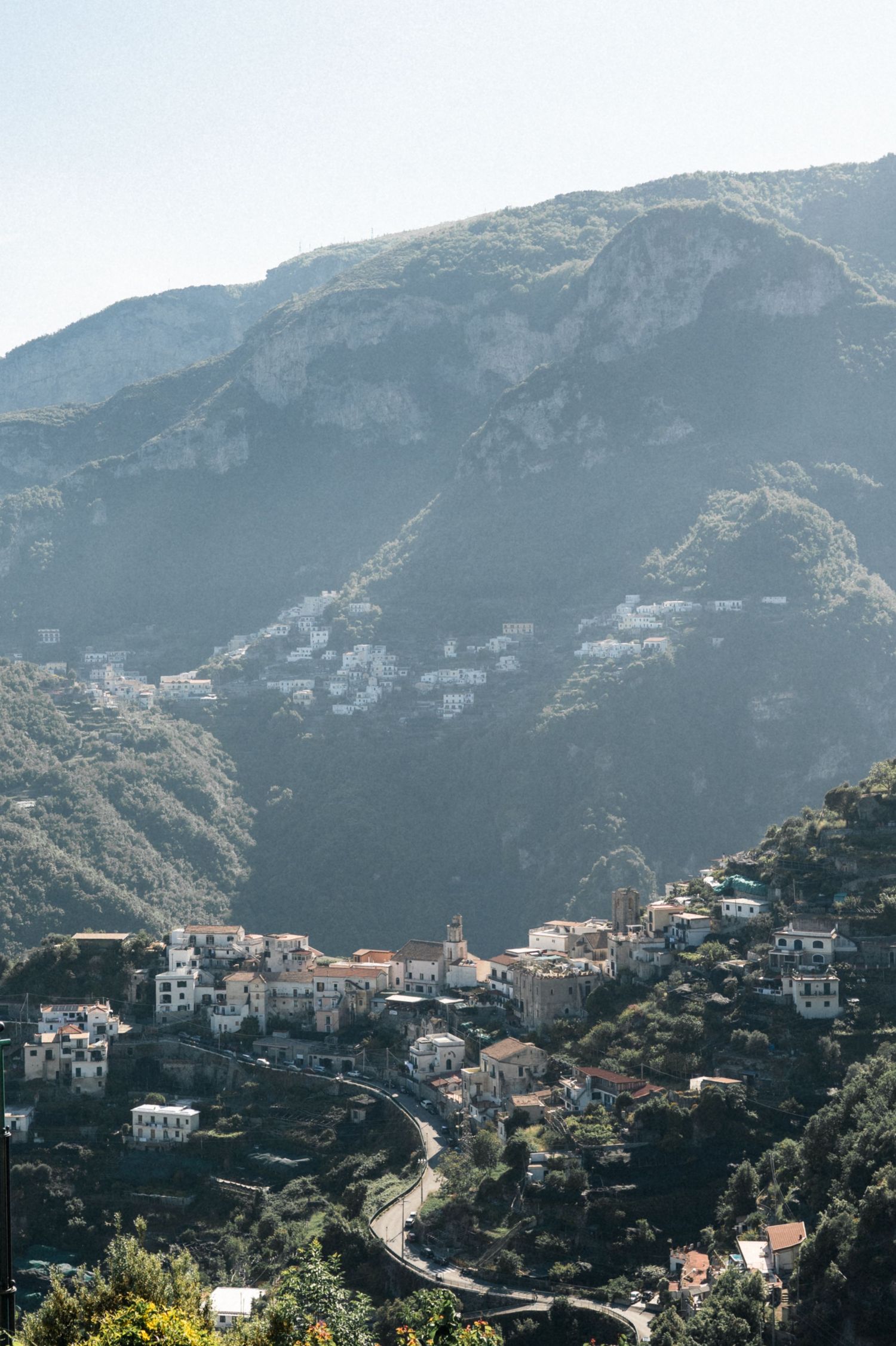 Scenic aerial view of a hillside Italian village nestled between lush green mountains on Amalfi Coast.