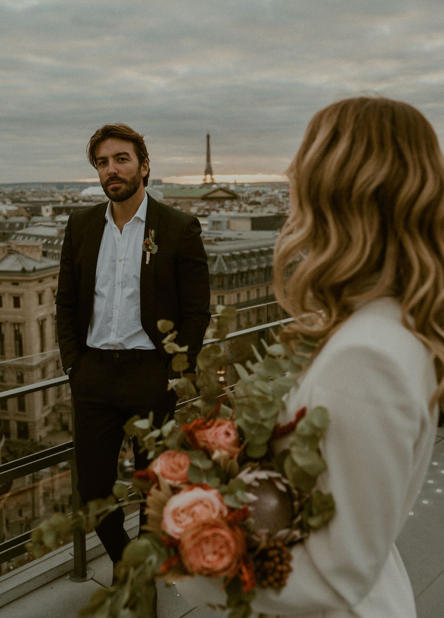 Romantic rooftop wedding portrait with Eiffel Tower visible in Paris skyline.
