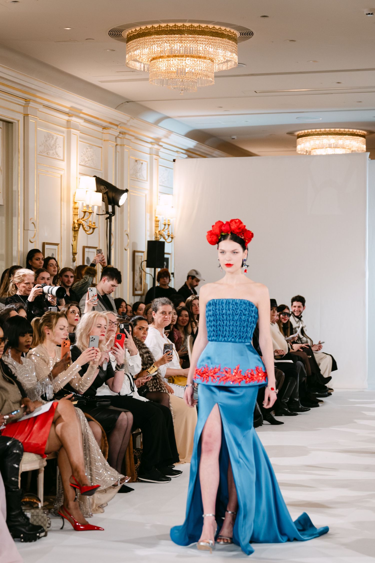 Model in blue strapless gown with red embroidery and floral crown walks couture runway.