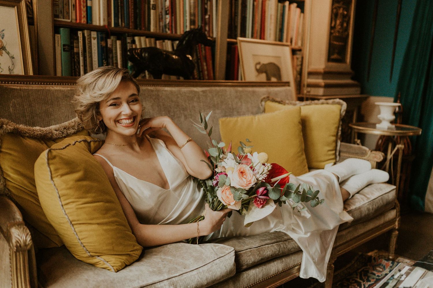 A candid wedding moment captured in a cozy library setting with yellow vintage furniture.