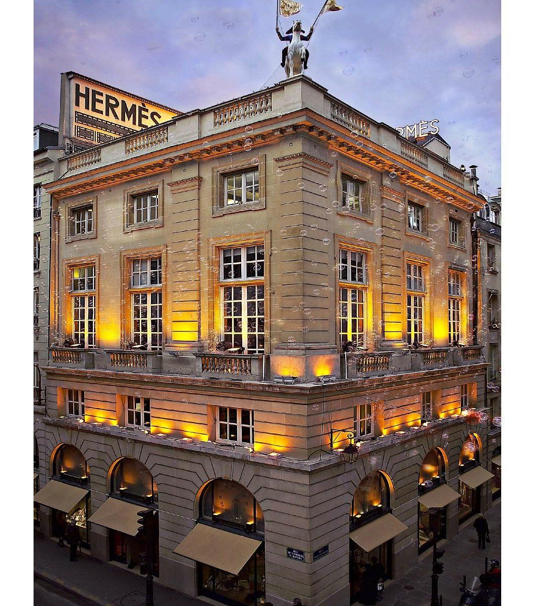 Illuminated Hermes luxury store building with classic architecture at dusk.