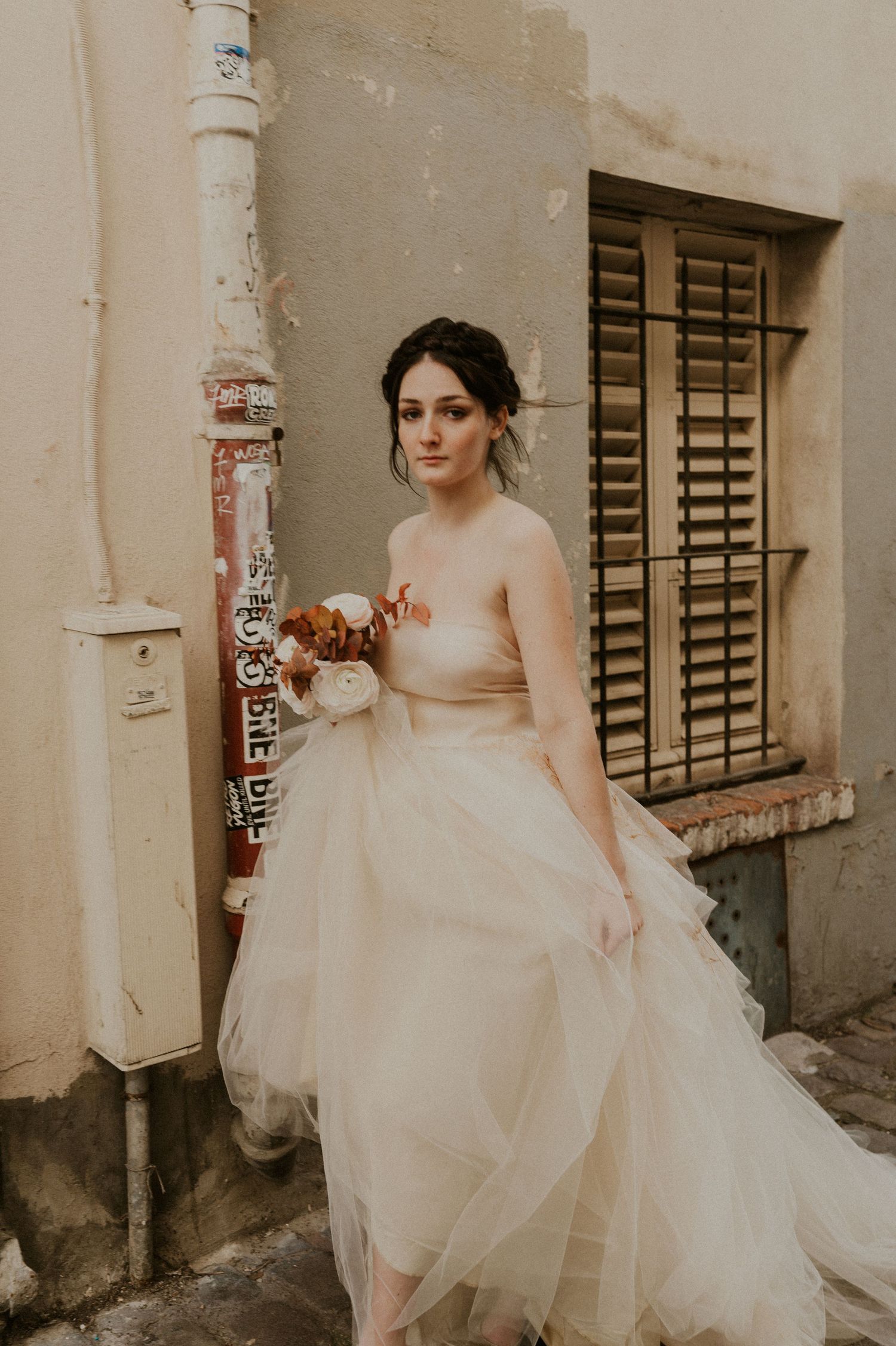 Romantic bridal portrait featuring a strapless tulle gown against vintage architecture.