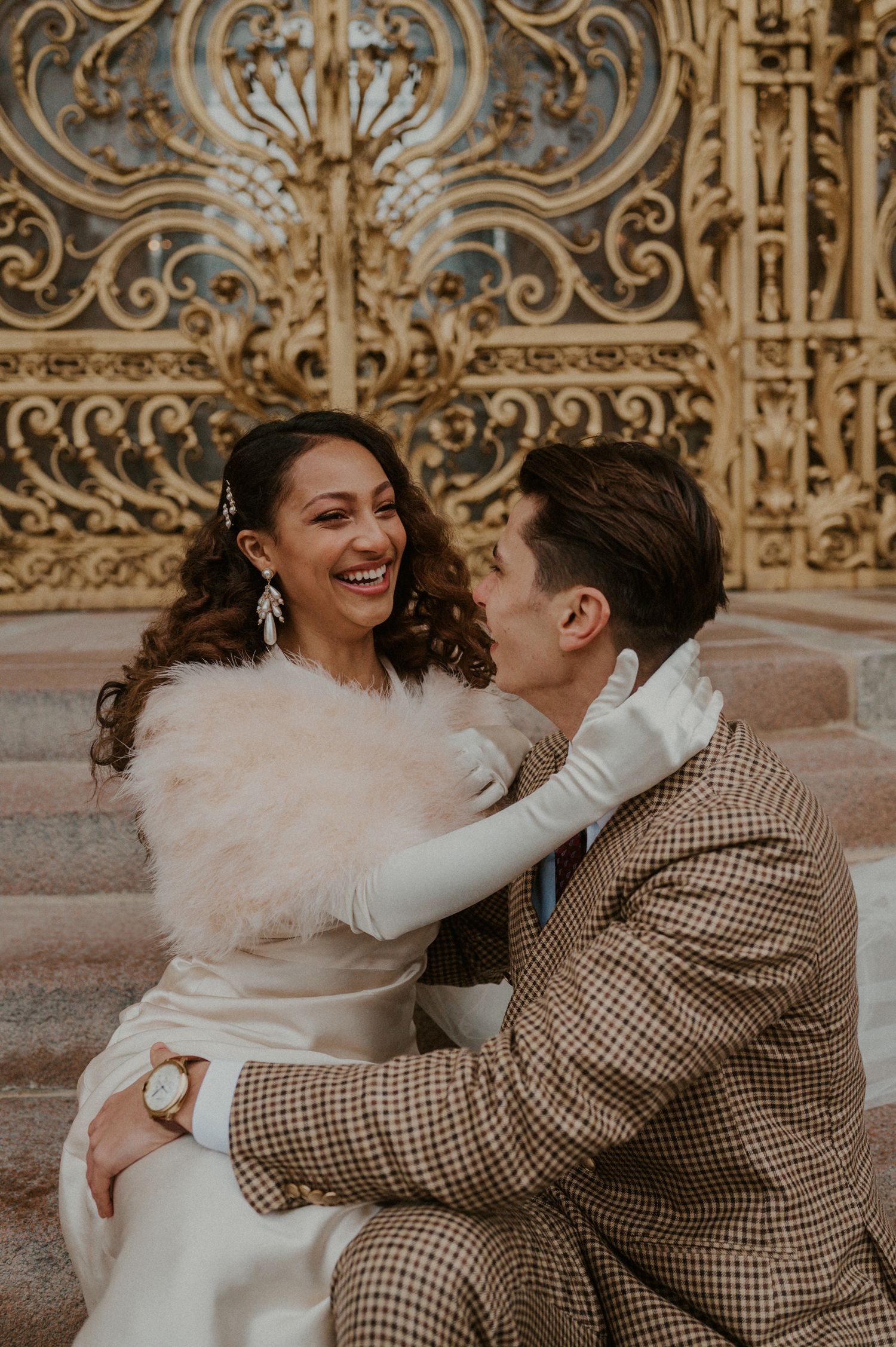 Joyful wedding couple sharing a candid moment on stone steps.