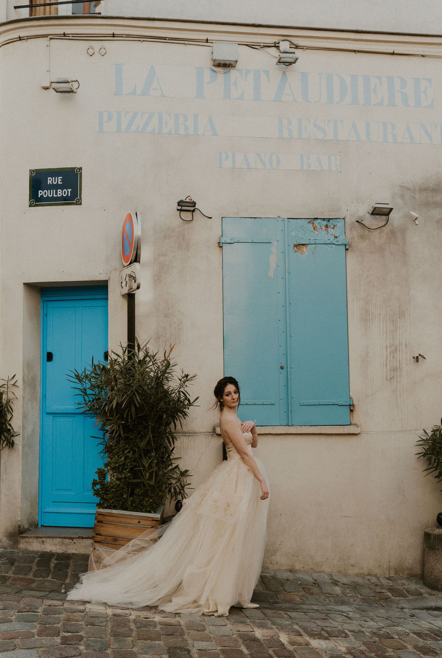 Bridal portrait at La Penzodiere featuring cream wedding gown against weathered white building with blue door.
