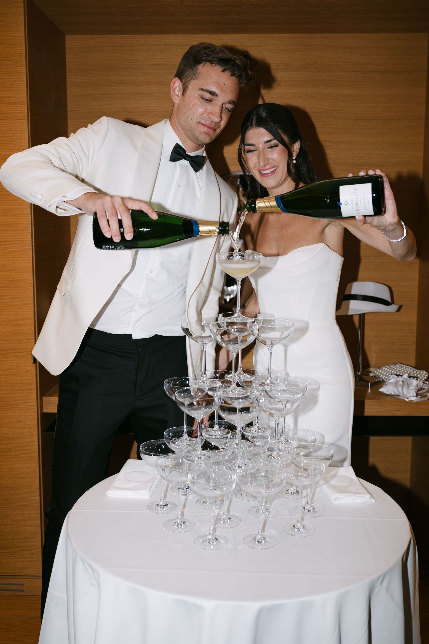 Servers pour champagne into a tower of elegant crystal glasses at an upscale event.